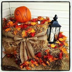 a pumpkin sitting on top of hay next to a lantern