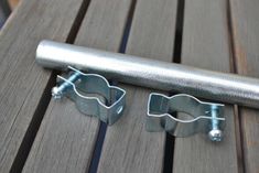 two pieces of metal sitting on top of a wooden table next to a pipe clamp