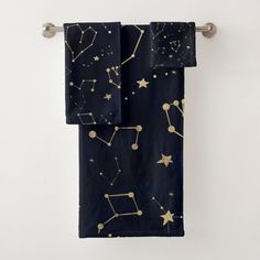 two towels hanging on a towel rack with gold stars and constellations printed on them