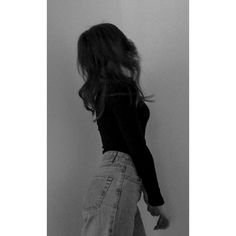 black and white photograph of woman in jeans leaning against wall with her hand on the floor