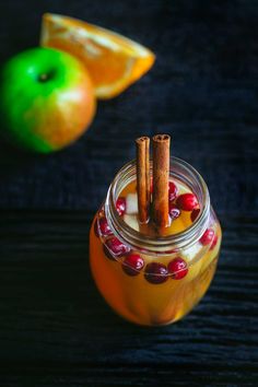 an apple cider with two cinnamon sticks sticking out of it's top next to some oranges