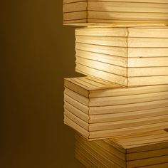 a stack of books sitting on top of a table next to a light fixture with a lamp in the middle