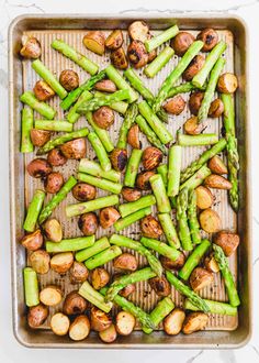 roasted asparagus and potatoes on a baking sheet in a roasting pan, ready to be cooked