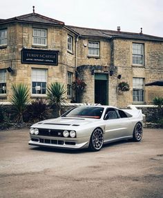 a white car parked in front of a stone building with windows and doors on it