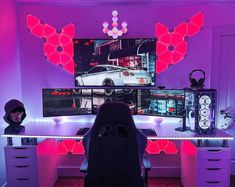 a computer desk with two monitors on it and a car in the background, all lit up by neon lights