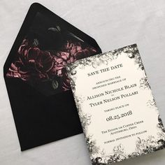 a black and white wedding save the date card with pink flowers on it, sitting next to an envelope