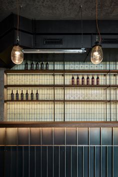 the lights are hanging from the bar above the bottles on the wall and behind the bars