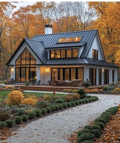 a house in the woods with lots of trees and shrubs around it, surrounded by fall foliage