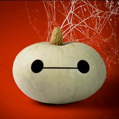 a white pumpkin with an angry face drawn on it's side, sitting in front of a red background