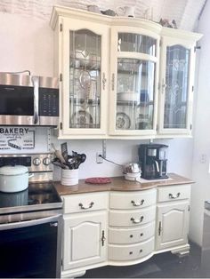 a kitchen with white cabinets and black stove top oven in the center, microwave on the far wall