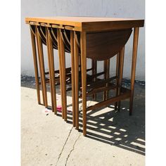 three wooden chairs sitting next to each other on top of a cement floor near a wall