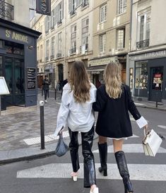 two women are walking down the street with shopping bags in their hands and one is wearing high heeled boots