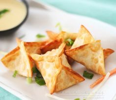 some food is sitting on a white plate with dipping sauce in the bowl behind it