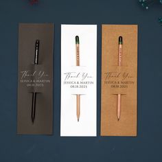 three different colored pens sitting next to each other on top of a paper bookmark