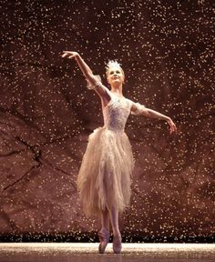 a ballerina in a white tutu and tiara with snow falling around her