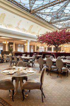 a restaurant with tables, chairs and chandeliers on the ceiling is decorated with red flowers