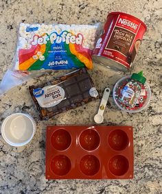 ingredients to make an ice cream sundae laid out on a marble counter top with chocolate, candy bars and other items