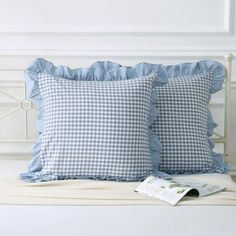 two blue and white pillows sitting on top of a bed next to each other,