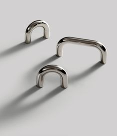 two metal handles are shown on a gray surface, one is shaped like an arch