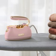 a pink phone sitting on top of a ironing board next to some folded towels