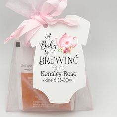 a baby is brewing gift bag with a pink bow on it's neck and label