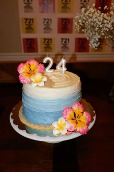 a blue and white cake with flowers on the top is sitting on a wooden table