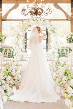 a bride standing in front of an archway with flowers