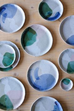 several plates with different designs on them sitting on a wooden table next to each other