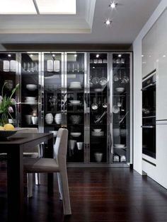 a dining room table and chairs in front of a glass wall with pots and pans on it