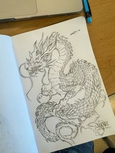 a drawing of a dragon sitting on top of a table next to a laptop computer