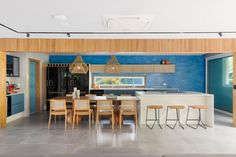 an open concept kitchen and dining area with blue walls, white countertops and wooden accents