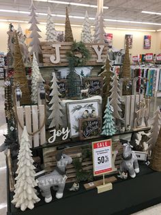 a christmas display in a store with trees and other holiday decorations on the shelf for sale