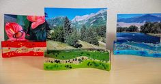 three cards with pictures of mountains and flowers on them sitting on a table next to each other