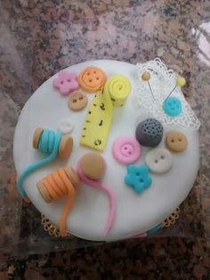 there is a cake with buttons and sewing pins on it