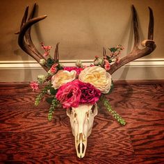 a deer skull with flowers on it's antlers is sitting on a table