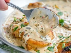 a spoon scooping some food out of a pot filled with white gravy