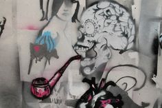 graffiti on the side of a building with a woman holding a pipe next to it