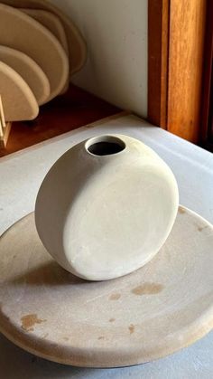 a white vase sitting on top of a plate