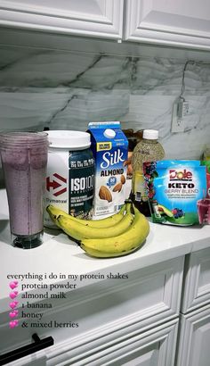 the ingredients for a smoothie are displayed on a kitchen counter with white cabinets and marble backsplash