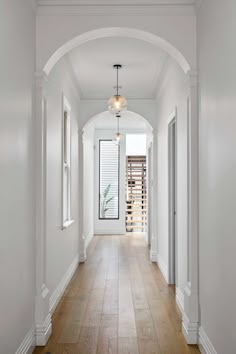 an empty hallway with white walls and wood floors