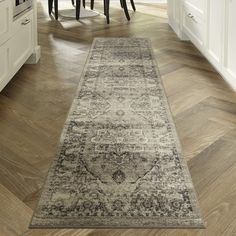 a large rug is in the middle of a kitchen with white cabinets and wooden floors