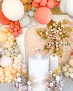 a white cake sitting on top of a table next to balloons and flowers in front of it