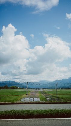 an empty field with mountains in the distance and water puddles on the ground below