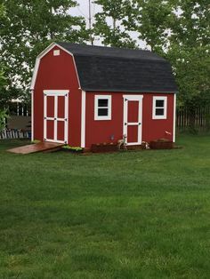 a small red barn sitting in the middle of a field