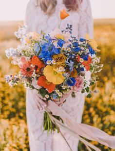 a woman in a white dress holding a bouquet of wildflowers and other flowers