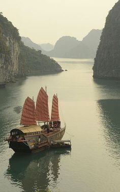 a boat floating on top of a large body of water next to tall mountains in the distance