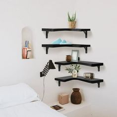 three black shelves on the wall above a bed