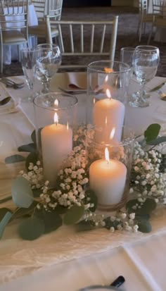 candles are lit on a table with flowers and greenery