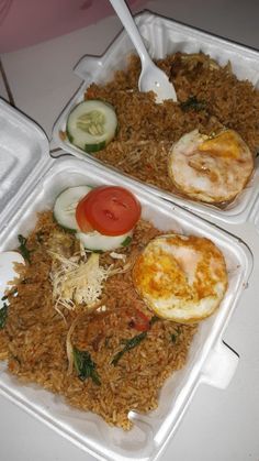 two takeout containers filled with rice and veggies, each containing an egg