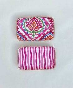 two pink and white rectangular shaped objects with designs on the top one has a red stripe, while the other is a multicolored pattern